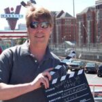 Mike Stiles holding clapboard in reference to healthcare podcast