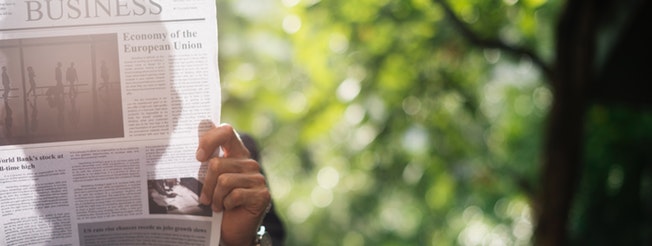 Hand of a man reading a newspaper in the park