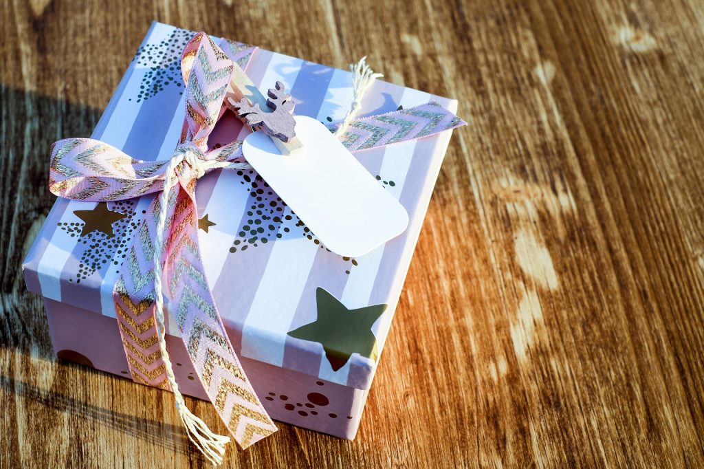 A gift in a purple box and ribbon sitting on a wood table