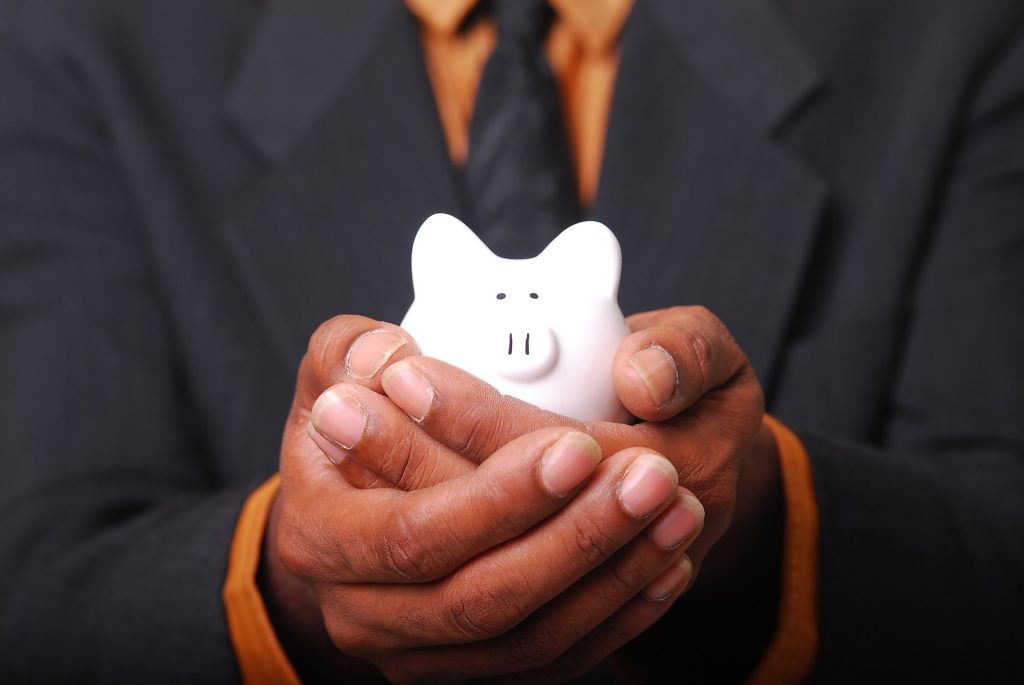 A pair of man's hands holding a little white pig toy